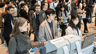 Annual Meeting attendees in line to print name badges at kiosks