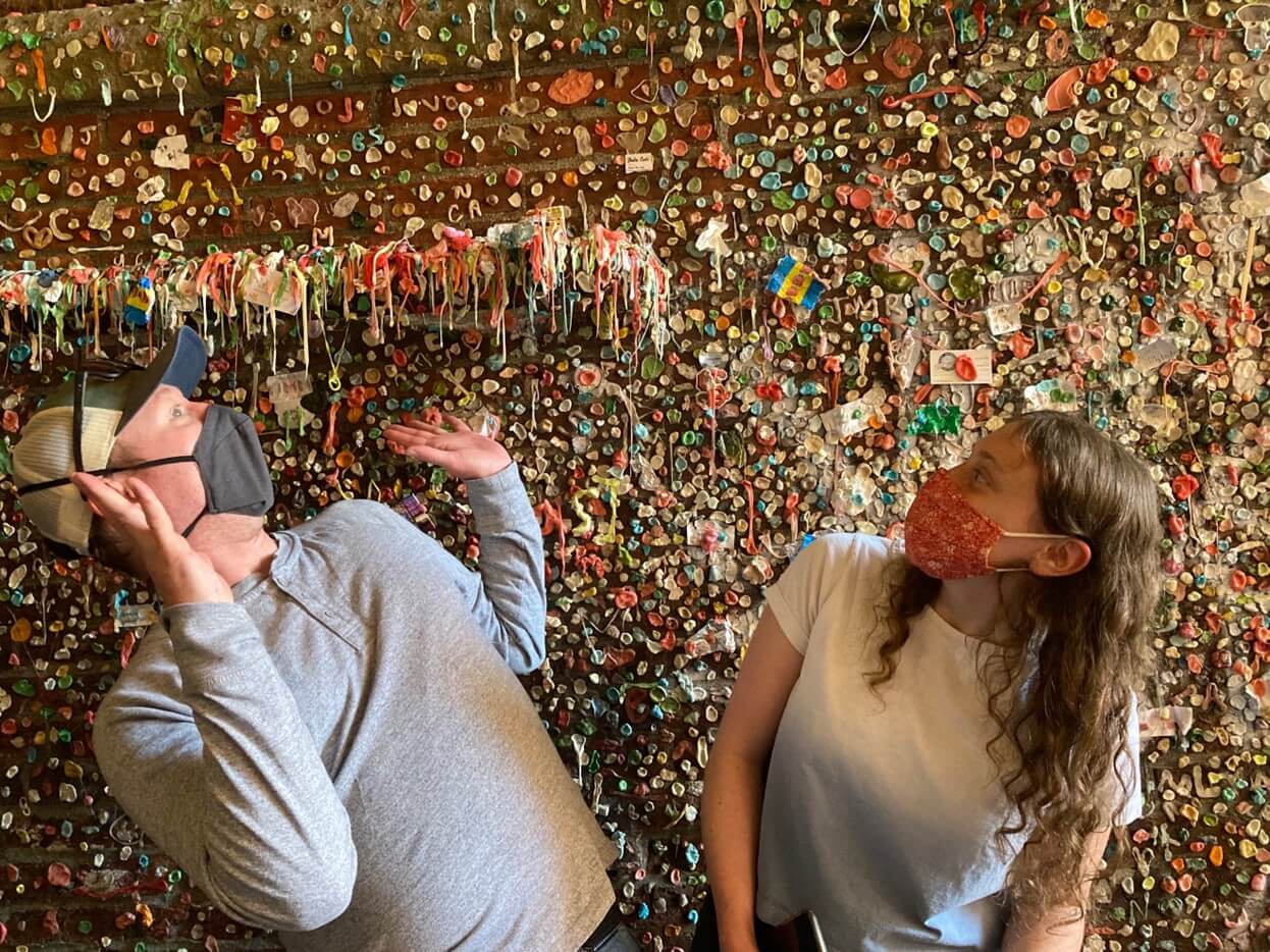 A couple standing in front of the Gum Wall at Pike Place Market