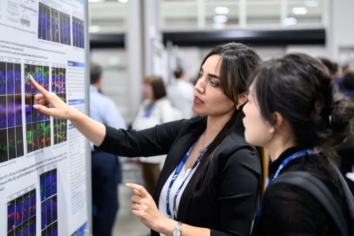 Presenter pointing to their poster and explaining their research to an Annual Meeting attendee