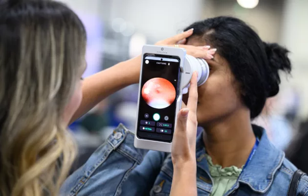 An individual using a cell phone attachment to perform an eye scan of another person