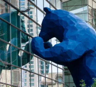 Large blue bear statue looking through a glass wall of the Colorado Convention Center